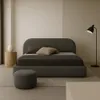 A minimalist bedroom with a large upholstered bed, a bedside table with a vase, and a floor lamp. Anteprima dell’immagine prodotto