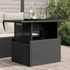 A black poly rattan garden table with a glass top is shown outdoors on a patio, next to a sofa with cushions. There are two glasses and a jug of water on the table. Produktbild-Vorschau