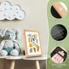 A children's picture frame with artwork is displayed on a table next to a stuffed toy. The image also includes close-up graphics highlighting product features. Produktbild-Vorschau