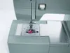 A close-up view of the needle and bobbin area of a gray Singer sewing machine. Anteprima dell’immagine prodotto