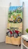 A towel with a tractor print is hanging on a towel rack in a bathroom. Produktbild-Vorschau