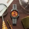 A watch is placed on a wooden surface with other items like a magnifying glass and a pen. Podgląd zdjęcia produktu