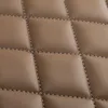 A close-up view of quilted light brown leather-look material with visible stitching. Produktbild-Vorschau