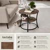 A round, two-tiered side table with a wood-grain finish and black metal legs, shown in a living room setting with two kittens playing around it. The image also includes a section with product features and branding. Produktbild-Vorschau