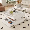 A modern living room with a white coffee table that has a lift-top mechanism and storage drawers, a laptop on the lift-top, and a sofa in the background. Produktbild-Vorschau