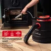 A person is using a LEHMANN ash vacuum cleaner to clean out a wood-burning stove. The vacuum is black with red accents and has a flexible hose. There are icons and text indicating its multi-functional capabilities. Produktbild-Vorschau