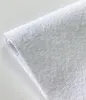 A close-up, angled view of a white terry cloth fabric, likely a mattress protector, against a plain white background. Náhľad obrázku produktu