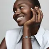 A woman is smiling and touching her face while wearing a bracelet. Anteprima dell’immagine prodotto