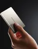 A hand holds a silver power bank against a dark background. Produktbild-Vorschau