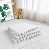 Stapel weißer ineinandergreifender Schaumstoffbodenmatten mit flauschiger Textur, auf weißem Teppich neben einem Teddybären Náhľad obrázku produktu
