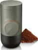 A portable espresso maker and a pile of coffee grounds. Produktbild-Vorschau