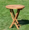 A round wooden folding table is set up on a grassy lawn. Produktbild-Vorschau