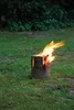A burning log fire in a grassy outdoor setting. Produktbild-Vorschau
