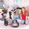 A young girl is sitting on the floor next to a twin doll stroller, surrounded by toys and decorations. Náhľad obrázku produktu