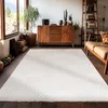 A living room with a wooden cabinet, plants, and a large rug. Anteprima dell’immagine prodotto