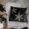 A black pillow with gold snowflakes and stars sits on a vintage chair next to a Christmas tree. Voir les images du produit