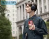 A young man wearing headphones is walking outdoors, holding a red phone case. Produktbild-Vorschau