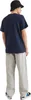 A person wearing a navy t-shirt and gray pants, viewed from the back. Voir les images du produit