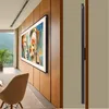 A modern living room with a large TV mounted on a wood-paneled wall, displaying abstract art. A chair is in the foreground. Anteprima dell’immagine prodotto