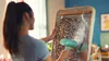 A woman is steaming a leopard print garment hanging on a hanger in front of a mirror. Náhľad obrázku produktu