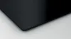 A close-up of the corner of a black induction cooktop. Voir les images du produit
