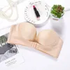 Beiger trägerloser BH mit vorderem Clipverschluss, flach auf weißer Fläche mit verschiedenen Accessoires ausgelegt Náhled obrázku produktu