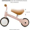 A pink balance bike with adjustable seat height indicated by stacked seat images and a measurement. Voir les images du produit