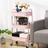 A pink three-tiered rolling cart filled with books, decorative items, and storage boxes, placed next to a gray sofa.