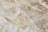A close-up view of a textured rug with a pattern of beige and gold threads. Anteprima dell’immagine prodotto