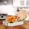 A roasted chicken in a roasting pan with a wooden cutting board in the background. Podgląd zdjęcia produktu