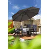 An outdoor dining set with chairs, a table, and an umbrella on a wooden deck, surrounded by greenery and a stone wall. Náhled obrázku produktu