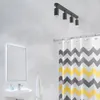 A modern bathroom with a sink, mirror, shower curtain, and ceiling lights. Voir les images du produit