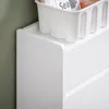 A close-up view of a white shoe cabinet with a white storage basket on top, against a green wall. Náhľad obrázku produktu