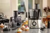 A collection of kitchen appliances, including food processors and a blender, are displayed on a countertop, along with several decorated cupcakes. Náhľad obrázku produktu