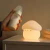 A hand holds a baby bottle next to a mushroom-shaped night light on a nightstand. Podgląd zdjęcia produktu