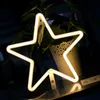 A neon star-shaped light is displayed in front of a potted plant. Produktbild-Vorschau