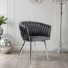 A gray velvet chair with a braided design and chrome legs is shown in a well-lit room with a chandelier and a decorative sphere. Anteprima dell’immagine prodotto
