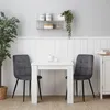 A white dining table with two gray chairs in a room with white paneled walls. Produktbild-Vorschau