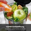 A hand is adding fruit and vegetables to a juicer. Produktbild-Vorschau