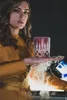 A woman holding a glass with smoke coming from it. Produktbild-Vorschau
