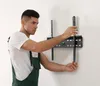 A man is installing a TV wall mount on a white wall. Produktbild-Vorschau