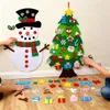 Children's hands decorating a felt Christmas tree and snowman on a wall. Produktbild-Vorschau