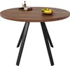 A round dining table with black metal legs, set against a white background. A bottle and glasses are on a tray on the table, along with a bowl of fruit. Produktbild-Vorschau