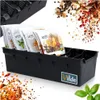 A black spice organizer filled with spice packets, with scattered spices and a basil leaf in the foreground. Anteprima dell’immagine prodotto