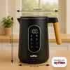 A black electric kettle with a wooden handle is shown on a wooden surface, with kitchen elements in the background. Dimensions are indicated with arrows and text. Produktbild-Vorschau