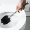 A hand holding a toilet brush over a toilet bowl. Náhled obrázku produktu