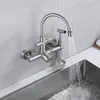A wall-mounted kitchen faucet with a sprayer is shown above a stainless steel sink with water running. Produktbild-Vorschau