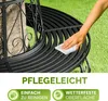 A hand is wiping a black metal garden bench that is wrapped around a tree. Produktbild-Vorschau