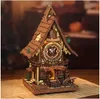 A detailed wooden model of a cuckoo clock, illuminated from within, sits on a surface covered with old papers. Náhľad obrázku produktu