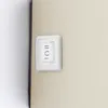 A close-up of a white light switch with black markings on a beige wall. Anteprima dell’immagine prodotto